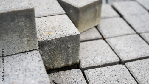 Close-up of stacked grey concrete paving blocks with a rough speckled surface and exposed aggregate. Detailed architectural texture for urban design and paving backgrounds

