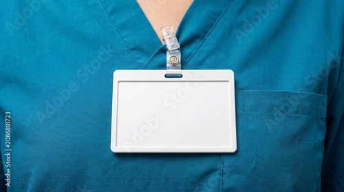 Close-up of blank white ID badge holder on blue medical scrubs