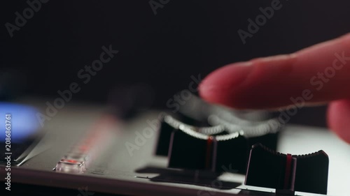 Music studio close up, Close up hands shot of sound engineer using mixing console, remote control for adjusting sound, audio mixer. Musician creates music, makes remix for DJ set. Sound