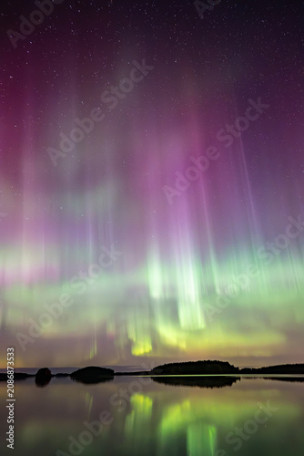 Northern lights dancing over calm lake in Farnebofjarden national park in north of Sweden.