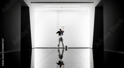 Painter Working On White Wall In A Modern Hallway Reflecting Light