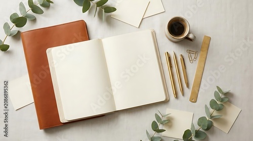 Open notebook and writing tools on a flat lay surface with plant accents