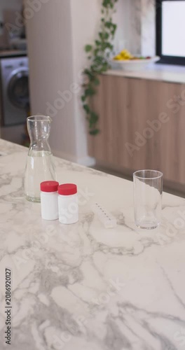 Vertical video: Camera is shifting focus while jars are sitting on marble top, revealing carafe