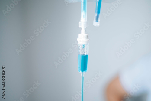 Close-up of an intravenous IV drip chamber filled with blue fluid in a modern healthcare facility.