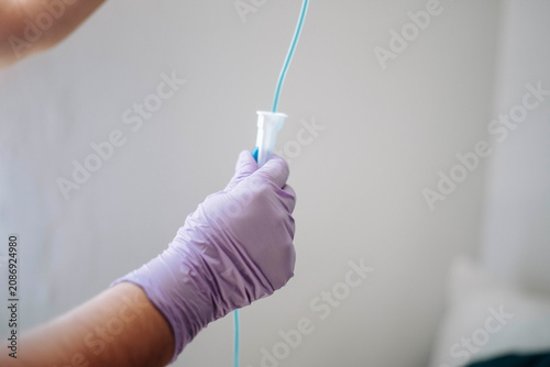 Close-up of a nurse holding an intravenous IV line while preparing infusion therapy in a modern healthcare environment.