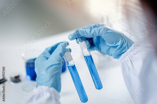 Foto Professional hands in blue gloves hold test tubes during a laboratory experiment