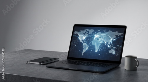 Modern laptop with digital global network map displayed on screen sitting on textured concrete desk surface with notebook and white ceramic mug in professional minimalist workspace office environment
