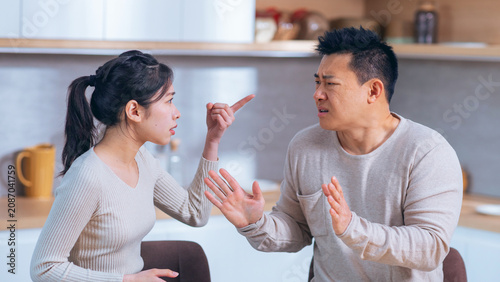 Photos Worried Asian Woman Arguing With Concerned Male Partner At Home, Engaging In Disagreement While Standing In Kitchen