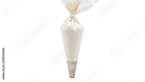 A transparent plastic piping bag filled with thick white icing, featuring a stainless steel nozzle tip, isolated on a plain white background, vertical