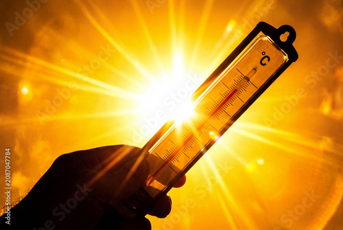 High temperatures - Heat wave / Summertime backdrop - Thermometer with yellow orange sky and sunlight