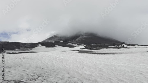 Rugged slopes of Mount Etna with snow patches and low clouds