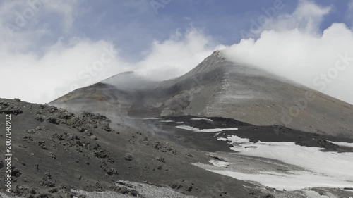 Dramatic volcanic summit of Mount Etna surrounded by moving cloud