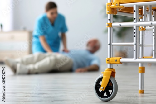 Caregiver and nurse helping an elderly senior after a fall accident in nursing home