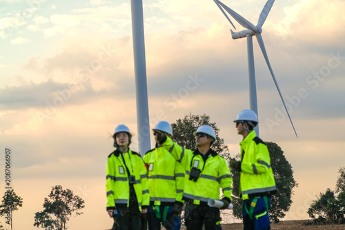 Картината върху платно The wind farm crew of four close the day with a roadside debrief on the park road under fading skies in pink pastel dusk on a working wind farm in rural Thailand