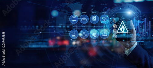 Photos Energy industry expert holding a mobile phone analyzing global Hydrocarbon Tech data on a holographic world map