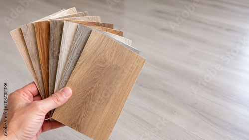 Hand Holding Luxury Vinyl Flooring Samples for Home Interior Design Selection