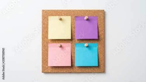 Cork board with four colorful blank sticky notes pinned isolated on white background