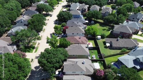 Single family properties border expansive green zones near Leonard and Helen Johns Community Park in Flower Mound, TX. Dark roof shingles integrate with heavy canopy cover, suburbs neighborhood
