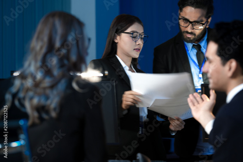 Foto Data integrity check night shift Diverse team meticulously audits financial performance comparing figures tablet screen printed reports ensuring accuracy crucial validation process underway hub
