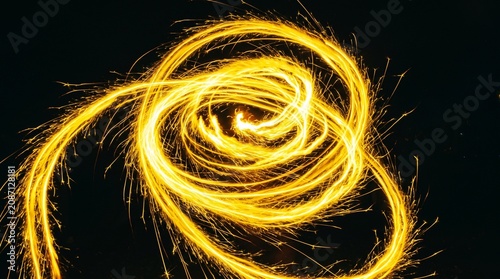 Abstract fiery spiral pattern created with sparks and light trails on dark background