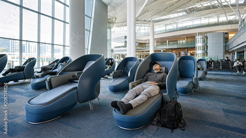 Passengers resting in modern blue sleeping pods at airport terminal
