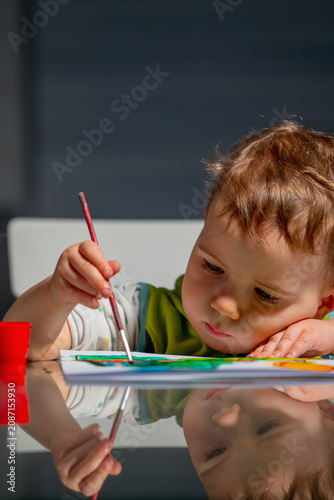Focused toddler painting with a brush during a creative learning activity at home.