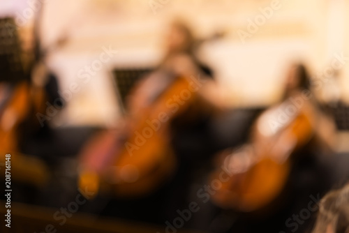 Blurred background shot of cellists playing instruments in a symphony orchestra