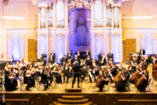 Blurred background of a symphony orchestra with conductor performing on stage in a concert hall