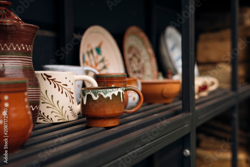 Artisan ceramic coffee cups displayed on pottery studio shelves, copy space.