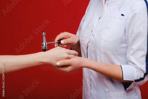 Tableau sur toile The doctor is holding a neurological hammer on a red background