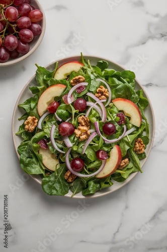 Colorful Salad With Greens, Apples, Grapes, and Nuts on a Round Plate on a Ma...