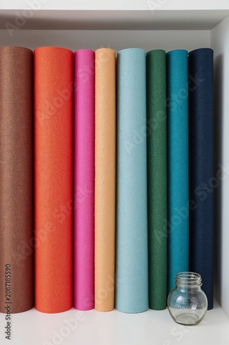 Display of Colorful Rolls of Paper Arranged on a Shelf in a Craft Room Settin...