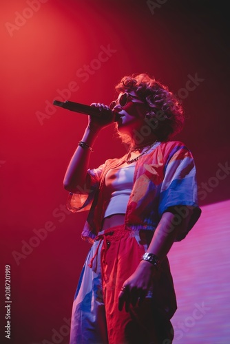 Curly Singer Performing Under Red Stage Lights