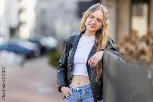 Young Woman Leaning on Railing in Leather Jacket Urban Casual Portrait With Glasses and Smile