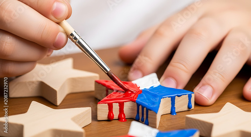 Child painting a wooden star with red white and blue acrylic paint