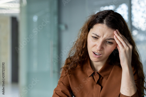Fotografie Woman feeling severe headache and discomfort, holding her temple while experienc