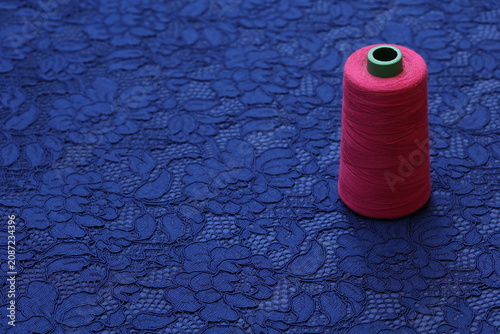 Obraz na plátně Neon pink sewing thread on thin royal blue stretchy lace fabric featuring an elegant, intricate floral pattern