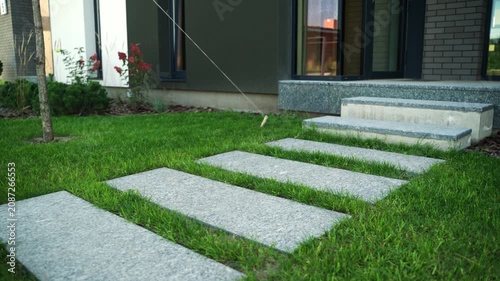 Modern stepping stone path leading to the entrance of a contemporary residential house through a green lawn, showcasing exterior design and landscape architecture