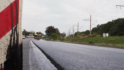 Road construction site with asphalt paving machinery laying fresh hot tarmac and compacting the surface with a steam roller