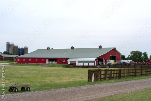 Canvas Print Classic red farm barn with grain silos in a rural landscape