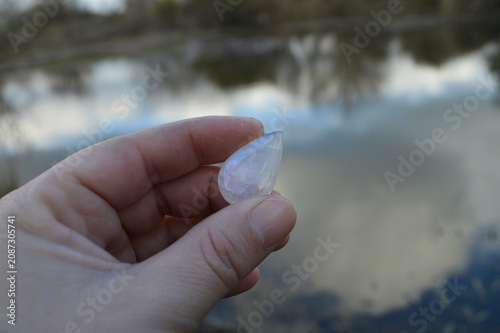 hand holding a moonstone on the lagoon 