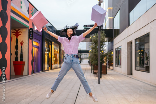 Woman jumping joyfully with shopping bags