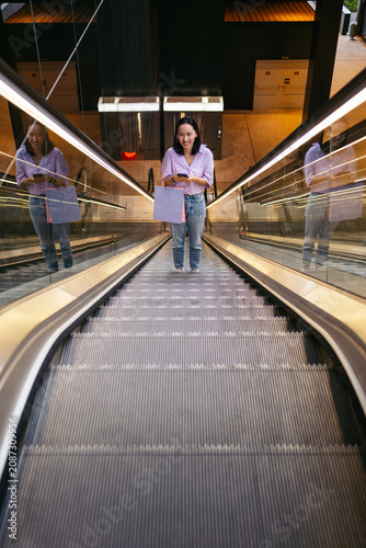 Asian woman with shopping bag on an escalator