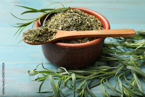 Картината върху платно Dry tarragon and fresh leaves on light blue wooden table, closeup