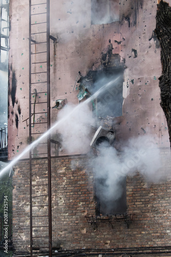 Tableau sur toile High-pressure water suppressing smoke and fire on a damaged building exterior