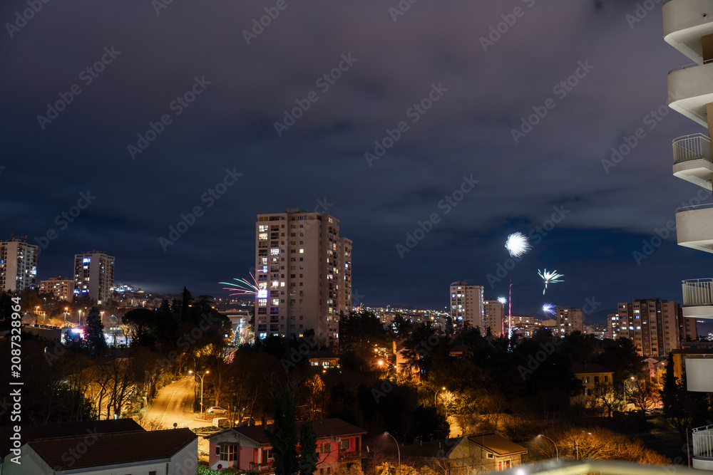 Fototapeta premium Night Rijeka city skyline with fireworks lighting up the sky during New Year’s Eve celebration. Concept of urban festivities, holiday traditions and winter celebrations