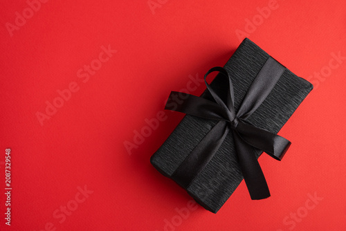 Black gift box creating elegant surprise on red background