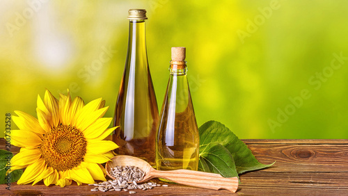 Photos Rural still-life - sunflower oil in bottles with flowers of sunflower (Helianthu