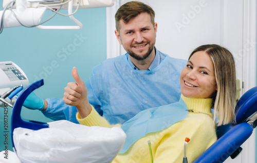 A beautiful girl patient is sitting in the dentist's office at the reception and next to the doctor