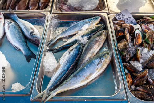 Fresh mackerel, sea bass and mixed mussels displayed on ice in metal trays at the famous Marsaxlokk fish market in Malta